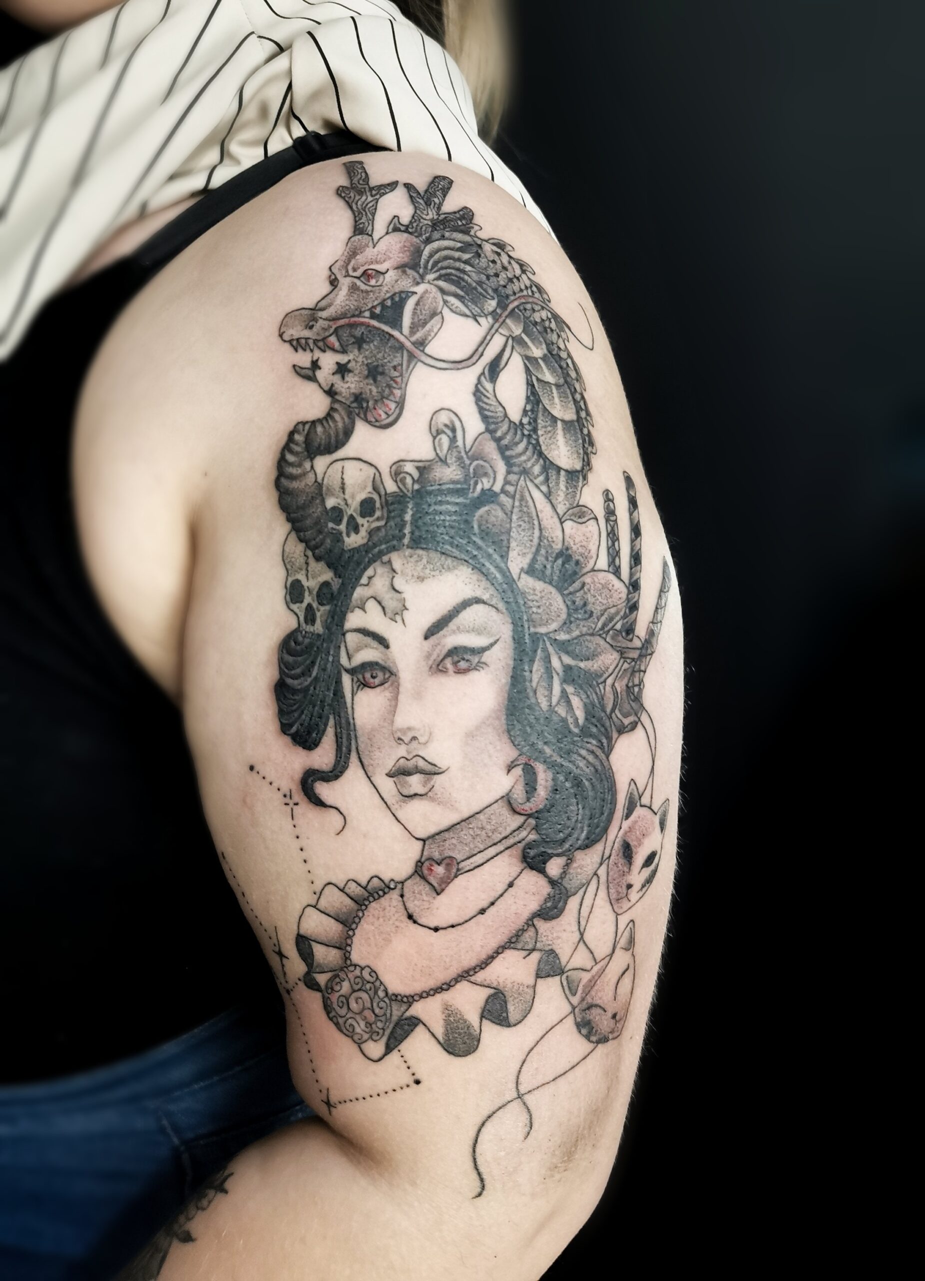 Photo d'un tatouage sur le haut du bras representant un portrait de femme avec un dragon ainsi que plusieurs éléments faisant références à divers manga (naruto, dragonball, sakura, one piece....)